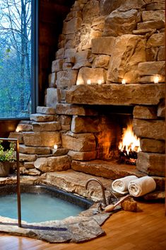 an indoor hot tub in front of a stone fireplace with lit candles on the side