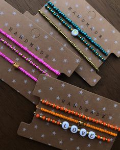 three bracelets with words and beads on them sitting on top of a wooden table