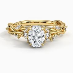 a yellow gold engagement ring with an oval cut diamond in the center and leaves on each side