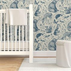 a baby's room with a crib and wallpaper that has animals on it