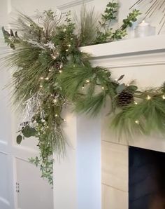 a mantel decorated with greenery and lights