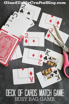 playing cards and scissors on a table with some pink scissors next to them that have been cut out