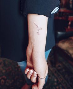 a woman's arm with a small bird tattoo on the left side of her arm