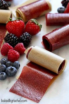 rolled up fruit and crackers on a counter with raspberries, blueberries, and strawberries