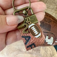 a person holding a keychain with a football on it