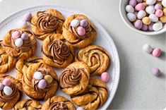 a white plate topped with pastries covered in chocolate and marshmallows next to a bowl of candy