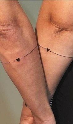 two women's legs with tattoos on them, one has hearts and the other has dots