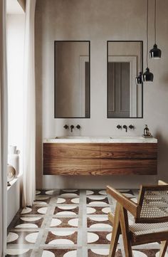 a bathroom with two sinks and mirrors on the wall next to a wooden chair in front of it