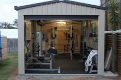 a garage with an open door and lots of exercise equipment in the back yard area