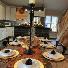 a dining room table is set with white plates and place settings for the thanksgiving dinner