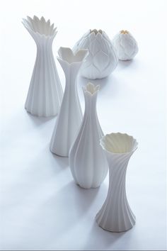 several white vases are lined up on the table