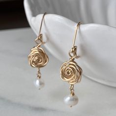 The Rose is a timeless symbol of love and beauty! Handcrafted Rose and Pearl Dangle Earrings will coordinate nicely with your pearl necklace - perfect for special occasion or everyday!  :: DETAILS :: ♥ Delicate handmade Rose connectors  measure approximately 1/2" in diameter and are handcrafted of 14K Gold fill, 14K Rose Gold fill, or Sterling Silver.  Each pair will vary slightly due to their handcrafted nature.   ♥ Freshwater Pearl dangles add interest and length for a total earring length of approximately 1 5/8". ♥ Leverback earwires are shown but French Hooks are available as an option in the drop down menu; hooks come with earring stops to provent loss.  All metals are 14K Gold fill, 14K Rose Gold fill, or Sterling Silver; heirloom quality. ♥ Arrives in a logo gift box with artist sig Elegant Rose Design Earrings For Gift, Elegant Adjustable Rose Design Earrings, Elegant Rose Drop Flower Earrings, Feminine Rose Gold Pearl Earrings Gift, Elegant Rose Flower Drop Earrings, Handmade Rose Gold Pearl Earrings For Anniversary, Elegant Rose Earrings With Ear Wire, Gold Rose Earrings For Gift, Rose Gold Flower Earrings With Roses