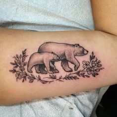 a woman's arm with a bear and cub tattoo on the left side of her arm