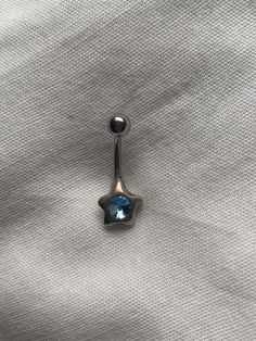 a single blue stone sitting on top of a piece of cloth with a metal hook