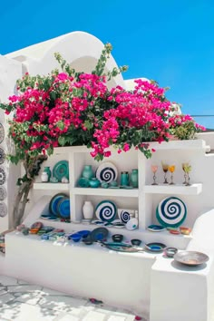 a white shelf with vases and flowers on it in front of a blue sky