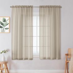 a living room scene with focus on the curtains and chair in the foreground while the wall is painted white