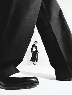 a black and white photo of a person's legs with a woman in the background