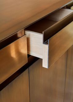 an open drawer on the side of a wooden cabinet with metal handles and drawers underneath it