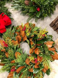 two wreaths with green and red flowers on top of snow next to other christmas decorations