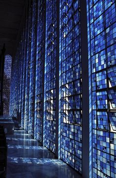 the inside of a building with many blue glass windows on each wall and stairs leading up to it