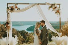 a bride and groom standing under an arch with flowers