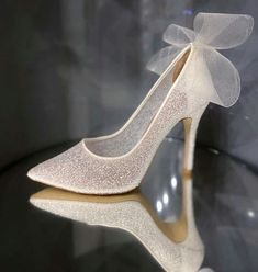 a pair of white high heels with a bow on top