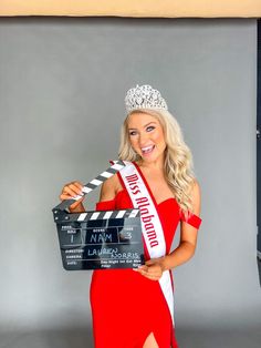 a woman in a red dress is holding a clapper and posing for a photo