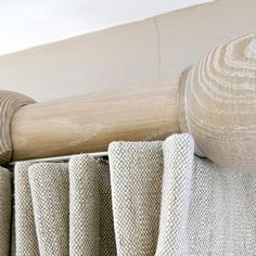 an upholstered bed with white linens and wooden posts on the headboard