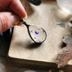 a hand holding a magnifying glass with stars and moon designs on the side