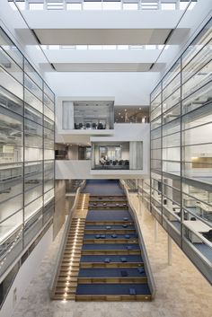 the inside of a building with many glass walls and stairs leading up to an upper floor