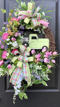 a wreath with a green truck and pink flowers on it is hanging on the front door