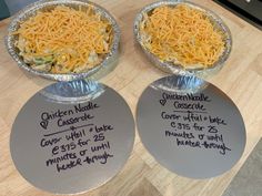 two pies covered in cheese on top of metal pans sitting on a table