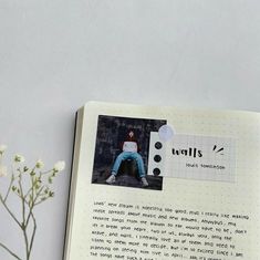 an open book with photos and text on the page next to a vase filled with flowers