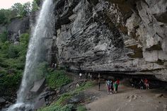 people are standing at the base of a waterfall