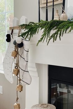 stockings hanging from the mantel in front of a fireplace decorated with pine cones and bells