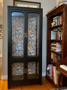 a black china cabinet sitting next to a book shelf