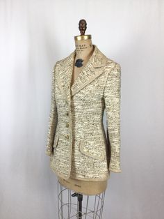 "Vintage 1960s cream woven textured silk suit blazer V-neck Notched collar trimmed in satouche ribbon which runs down front, along hem, pocket flaps and sleeve hems Four creamy marbled buttons down front for closure Darts and seams for a fitted fit Two faux flap pockets at front Long sleeves with a straight hem and trimmed with a single button Back has shoulder darts, and princess darts Lined in beige nylon MEASUREMENTS: Fits like a Medium Blazer: Shoulders: 16\" Bust: 36\" Waist: 32\" Hips: 38\ 60s Suit, Lilli Ann, Cream Blazer, Shirtwaist Dress, Silk Suit, Lace Shift Dress, Striped Blazer, Womens Blazers, Jacket Vintage