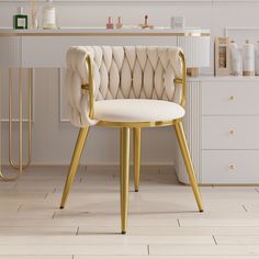 a white chair with gold legs in front of a vanity and counter top, next to a sink