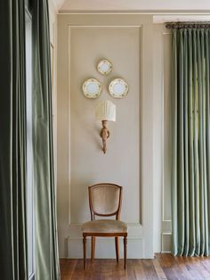 a chair sitting in front of a window next to a wall with plates on it