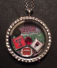 a necklace that has some items in it on top of a black surface with a football field and stadium in the background