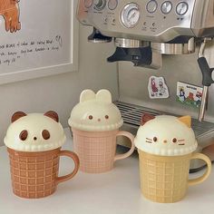 three coffee mugs decorated like animals sitting next to an espresso machine on a counter