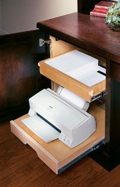 an open drawer on the side of a wooden desk with books and papers in it