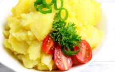 mashed potatoes with tomatoes and parsley in a white bowl