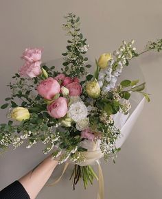 a bouquet of flowers is being held up by someone's hand on the wall