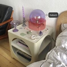 a table with a lamp on it next to a chair and a book shelf in the corner