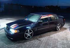 a black car parked on the side of a road at night with its lights on