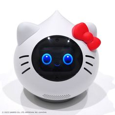 a white hello kitty alarm clock with blue eyes and a red bow on its head