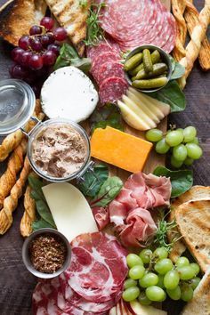 an assortment of cheeses, meats, and breads on a platter