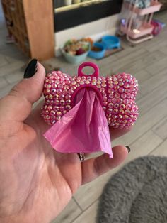 a hand holding a small pink bow shaped object