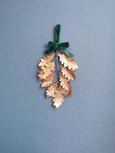 an oak leaf ornament hanging from a green ribbon on a blue background with copy space